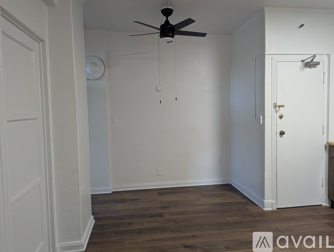 A room with a ceiling fan and wooden floors.