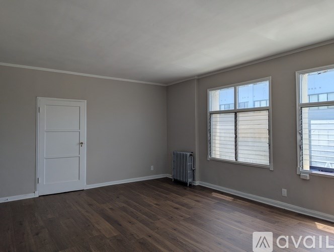 A room with a door, a radiator, and a window with blinds.