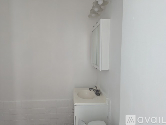 A white sink is mounted on a white cabinet in a white bathroom.