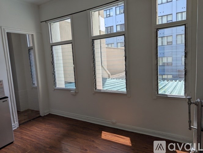 A room with wooden floors and three windows.