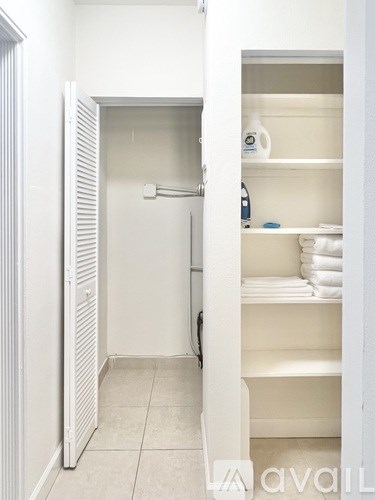 A white bathroom with a towel rack and towels on the shelf.