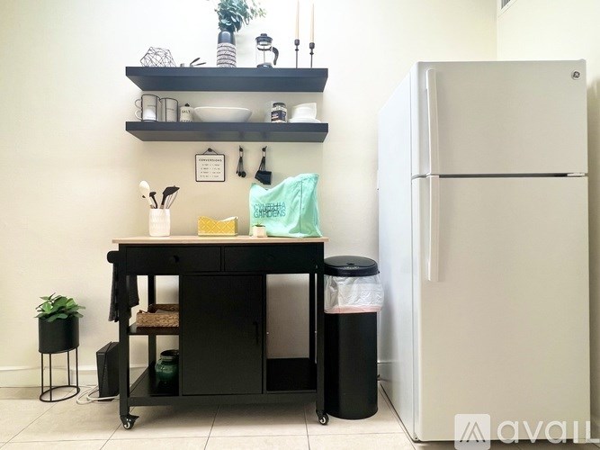 A kitchen with a black counter and a white fridge.