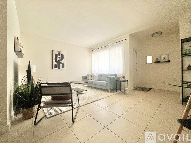 A living room with a sofa, chair, and potted plant.