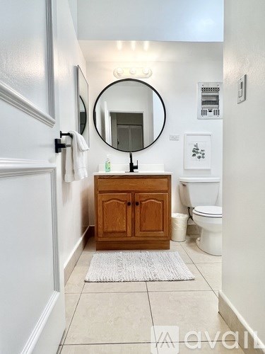 A bathroom with a round mirror and a wooden cabinet.