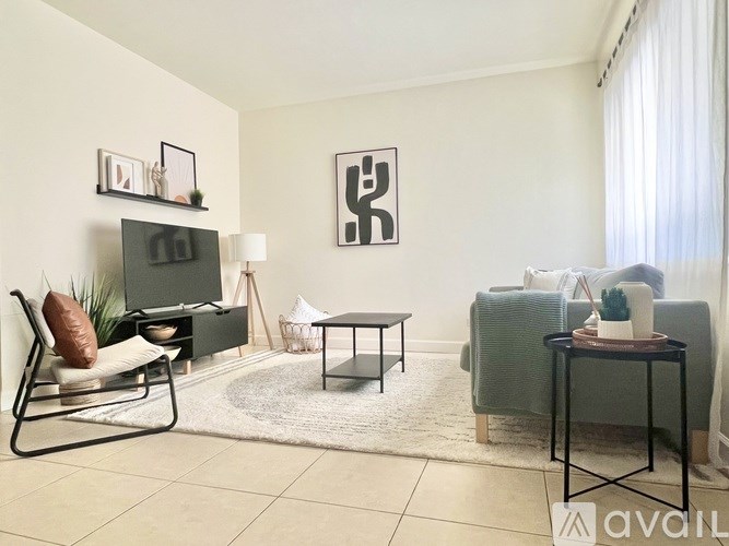 A living room with a white couch, a black chair, a white rug, and a black and white picture on the wall.