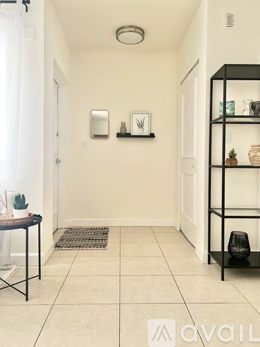 A hallway with a black shelf on the right and a rug on the floor.