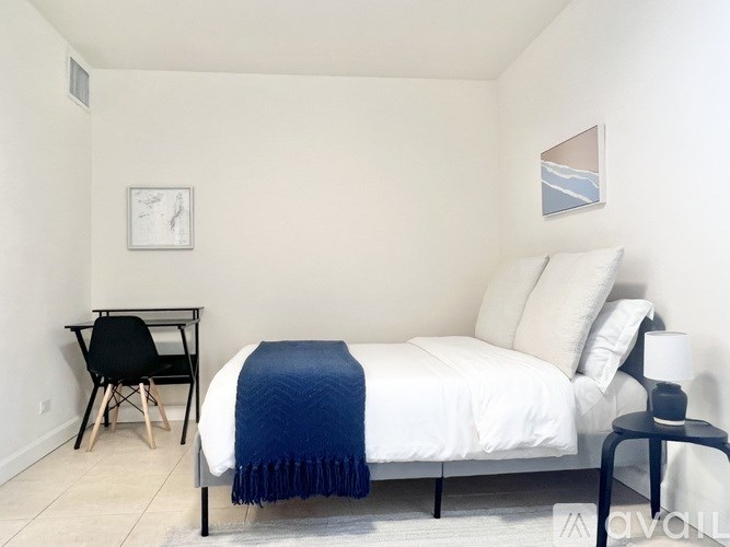 A bedroom with a bed, chair, and a picture on the wall.