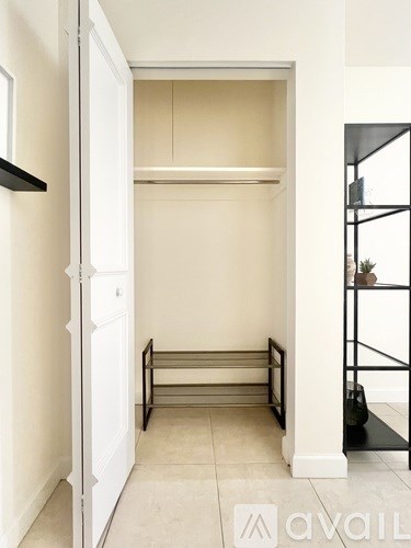 A white door is open to a small room with a bench.
