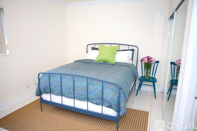 A bed with a blue comforter and a green pillow is in the image.