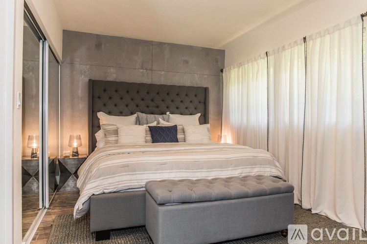 A bedroom with a large bed and a grey ottoman.
