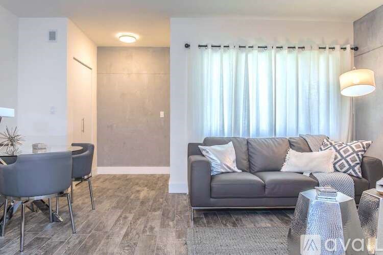 A living room with a grey couch, a grey chair, a grey coffee table, and a grey rug.