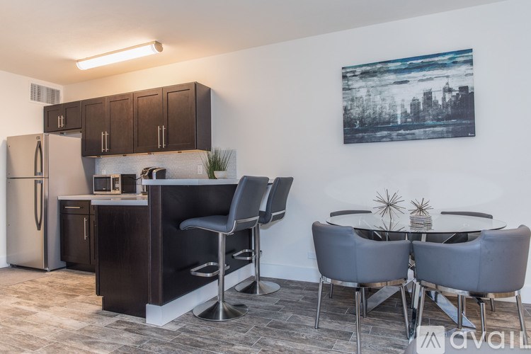 A kitchen with a refrigerator, bar stools, and a dining table with chairs.