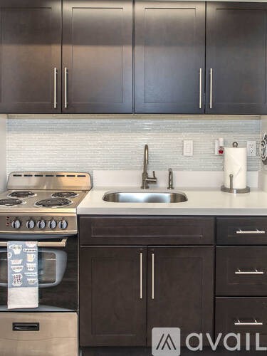A kitchen with dark brown cabinets and a stainless steel oven.