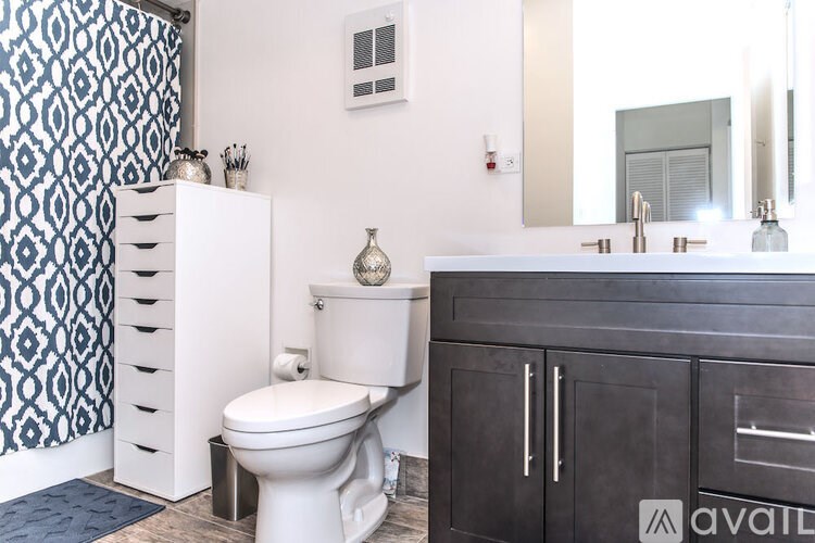 A bathroom with a toilet, sink, and a cabinet.