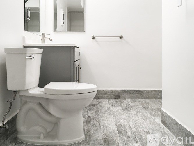 A white toilet with a white bidet is in a bathroom with a grey floor and a white wall.