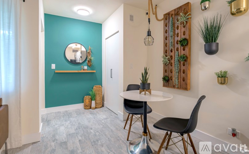 A room with a round table and chairs with a green wall and a mirror.
