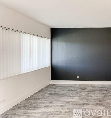 A room with a black wall and a window with white blinds.