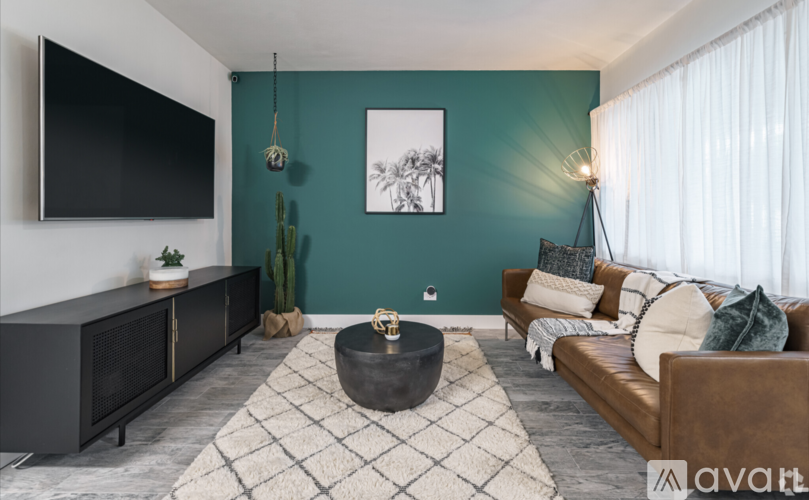 A living room with a flat screen TV, a couch, a coffee table, and a rug.