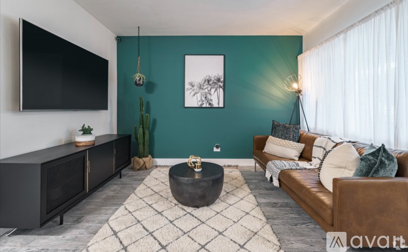 A living room with a flat screen TV, a couch, a coffee table, and a rug.