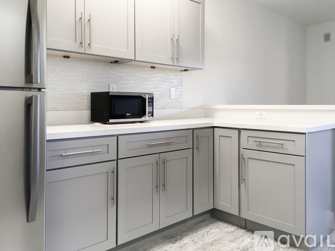 A kitchen with white cabinets and a black microwave.