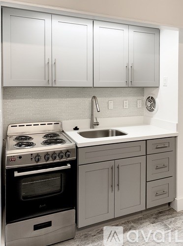 A modern kitchen with a stove, sink, and cabinets.