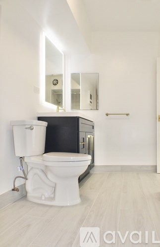 A white toilet with a bidet attachment is in a bathroom with a mirror above it.