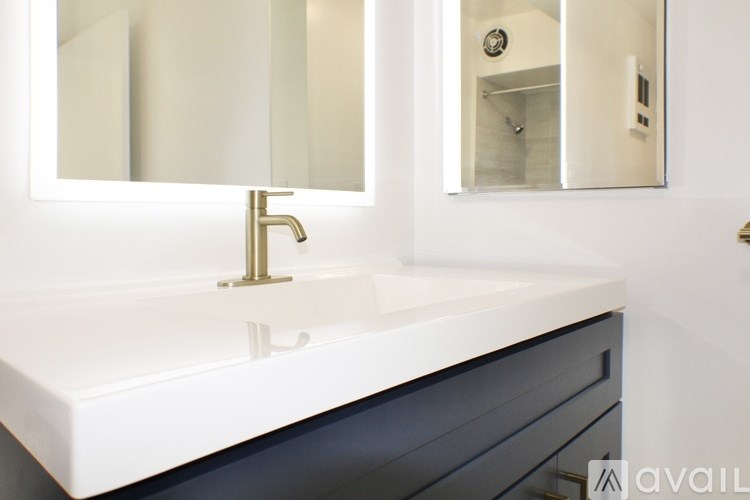 A bathroom vanity with a white countertop and a gold faucet.