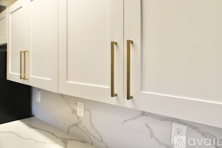 A kitchen with white cabinets and marble countertops.