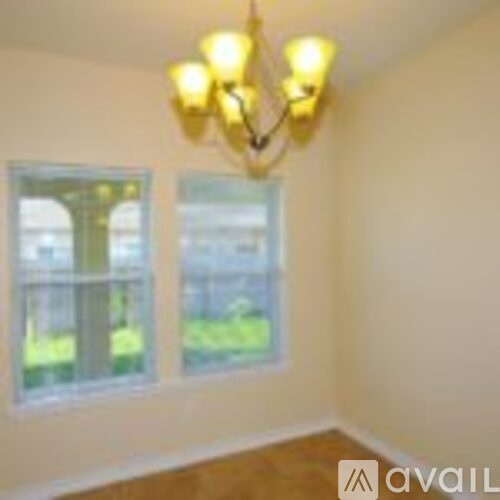 A room with a chandelier and two windows.