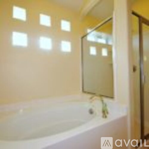 A white bathtub with a glass door and a mirror above it.