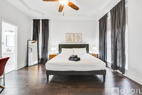 A bedroom with a large bed and a ceiling fan.