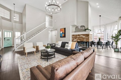 A living room with a brown leather couch and a fireplace.