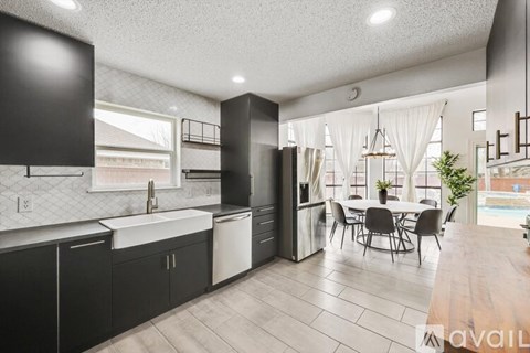 A modern kitchen with black cabinets and a dining table.