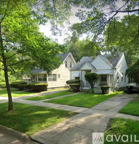 A house with a white exterior and a tree in front of it.