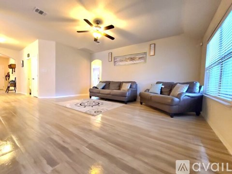 A living room with two grey couches and a ceiling fan.