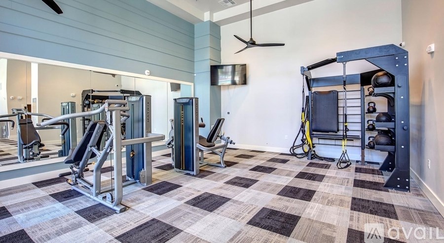 A gym with a variety of equipment including a squat rack, bench press, and a weight rack.