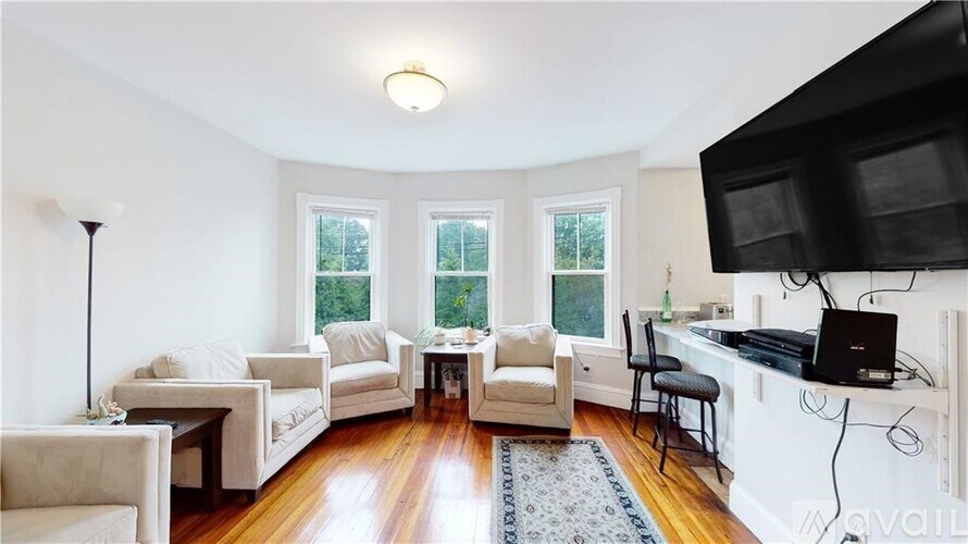 A living room with a television, a couch, a chair, and a table.
