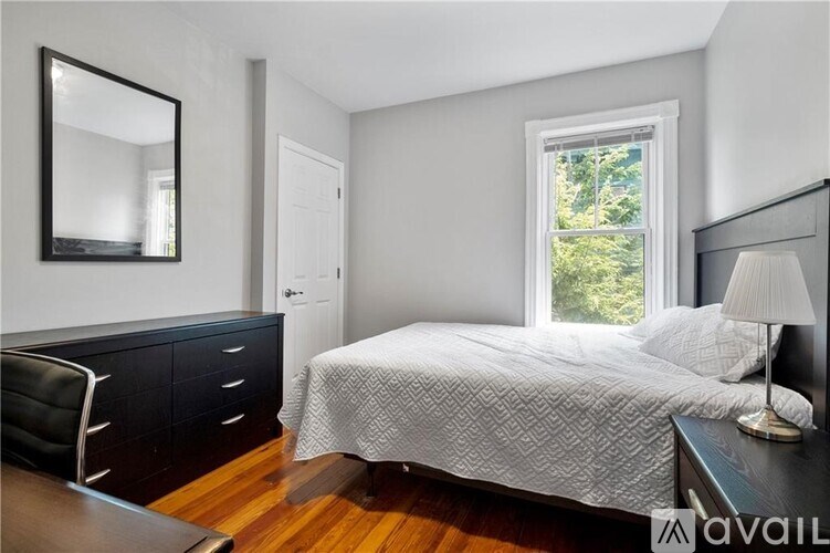 A bedroom with a bed, chair, and a mirror on the wall.