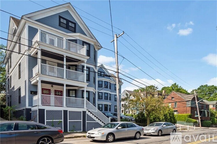 A two-story building with a balcony and a car parked in front.