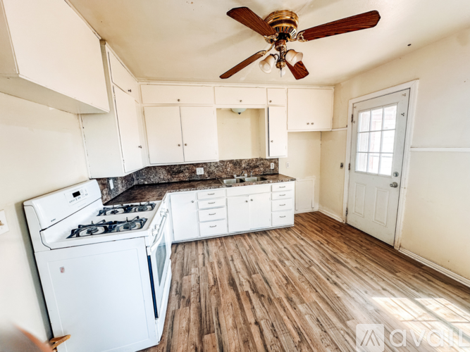 A kitchen with a white stove and cabinets.