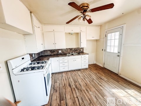 A kitchen with a white stove and cabinets.
