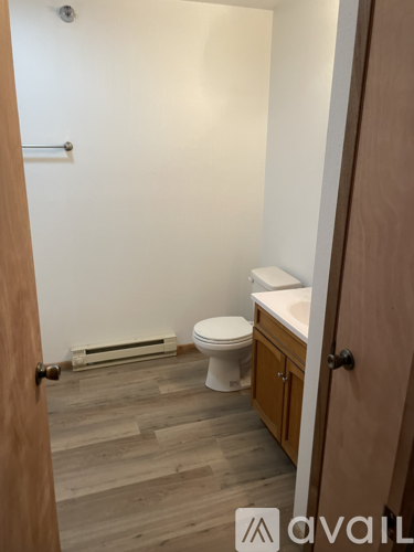 A bathroom with a toilet, sink, and wooden floors.