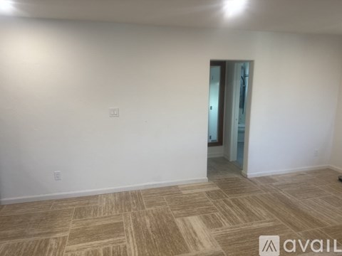 A room with a wooden floor and a door leading to another room.