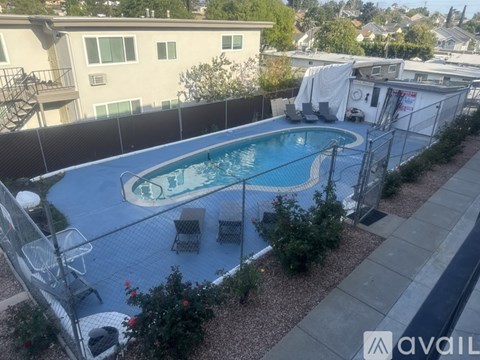 A pool surrounded by a fence and chairs.
