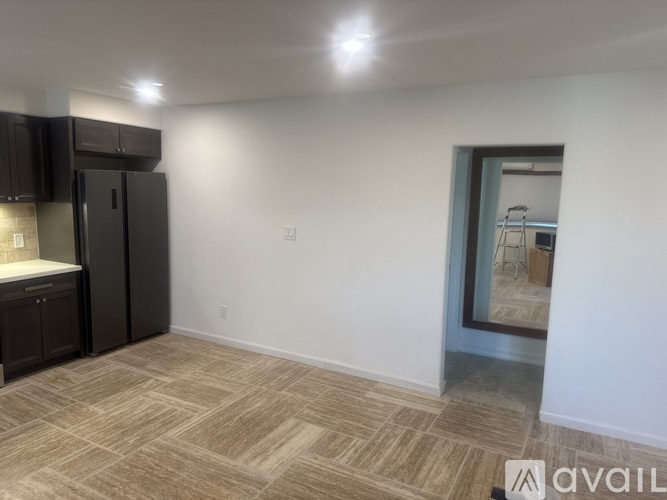 A kitchen area with a refrigerator, cabinets, and a countertop.