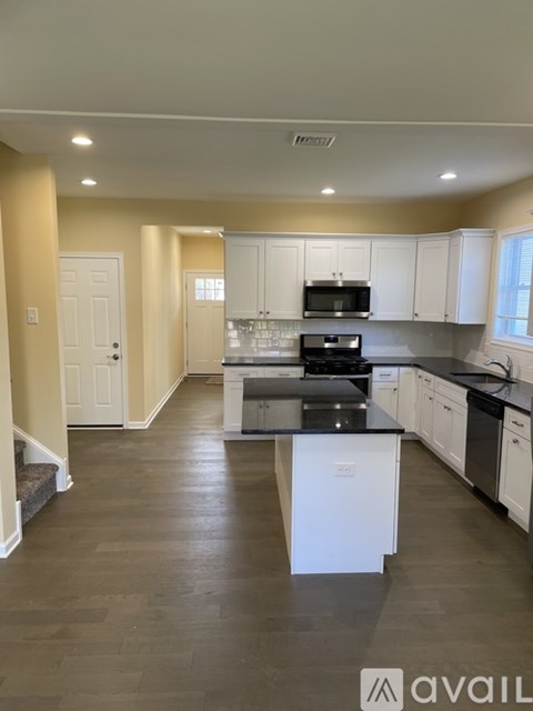 A kitchen with white cabinets and black appliances.