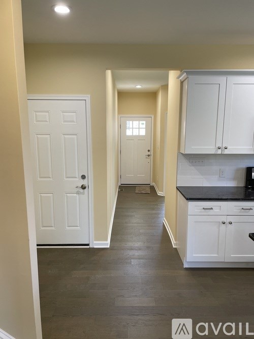 A hallway with white doors and cabinets.