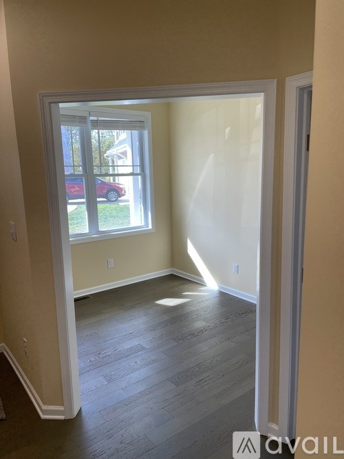 A room with a window and a wooden floor.