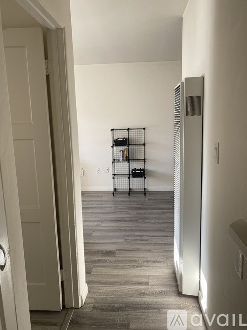 A hallway with a white door and a black wire shelf.
