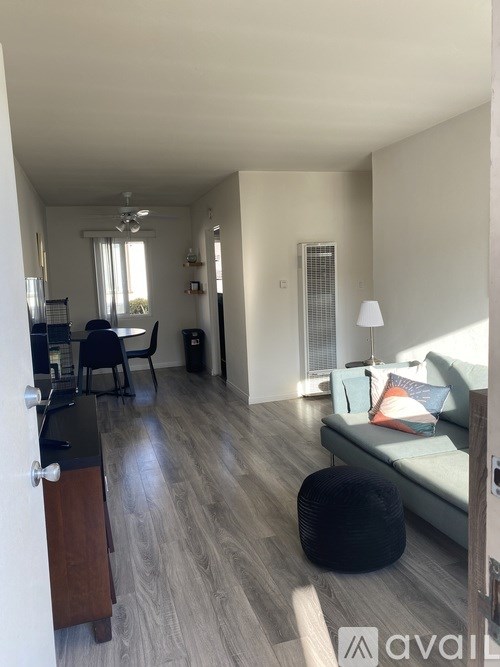 A room with wooden flooring and white walls, with sunlight streaming in through a window.